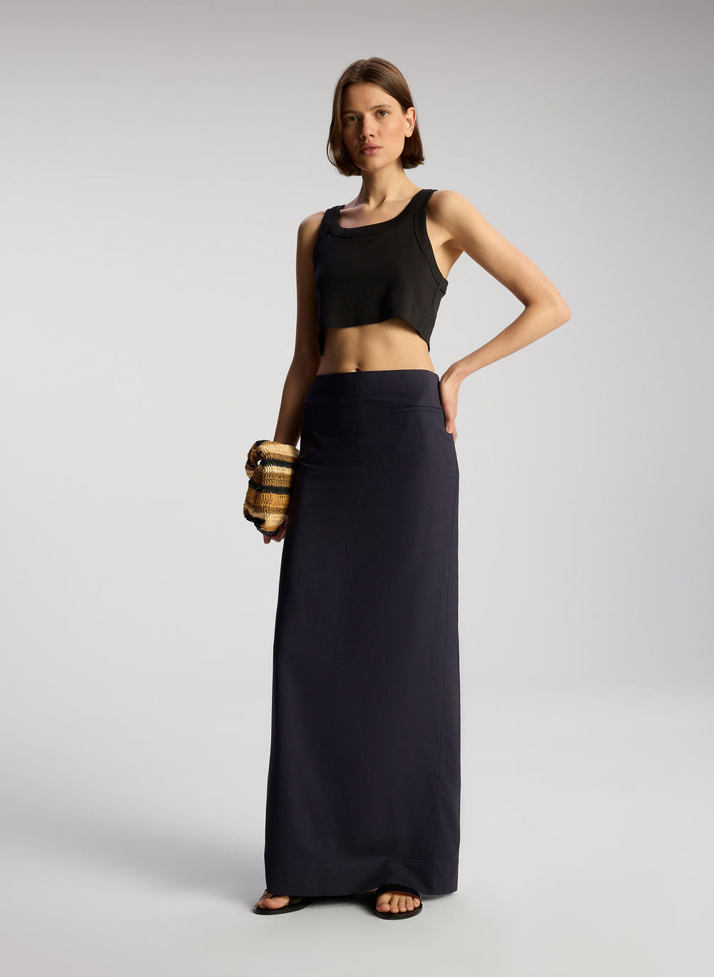 side view of woman wearing black cropped rib tank top with black maxi skirt