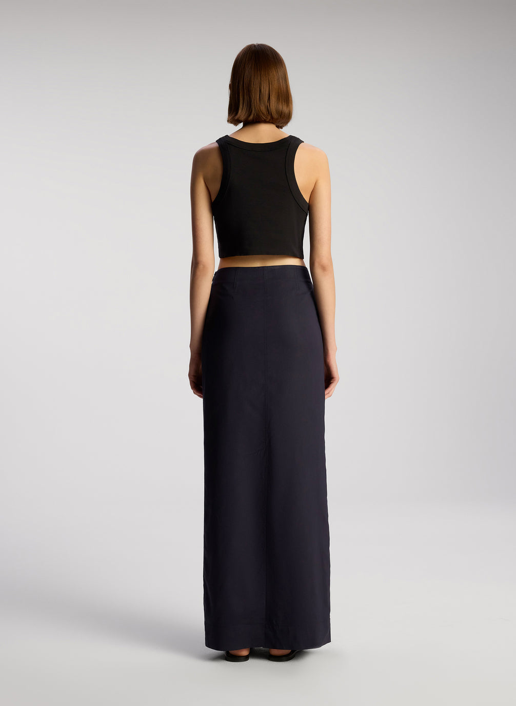 back view of woman wearing black cropped rib tank top with black maxi skirt