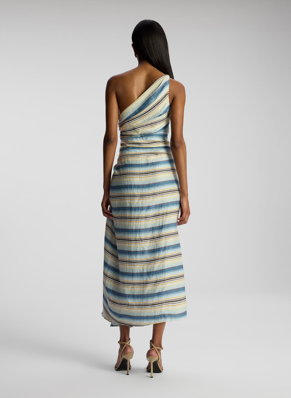 back view of woman wearing one shoulder striped midi dress