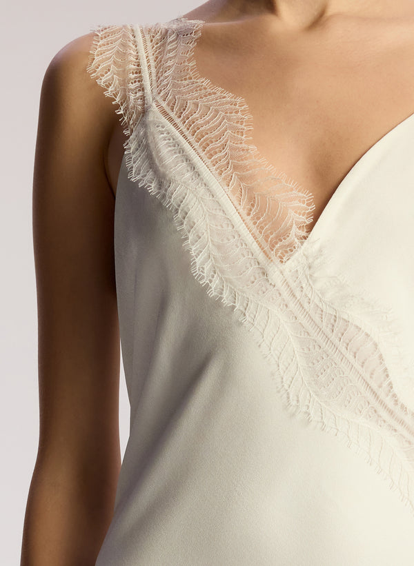 detail view of woman wearing off white lace trimmed midi dress