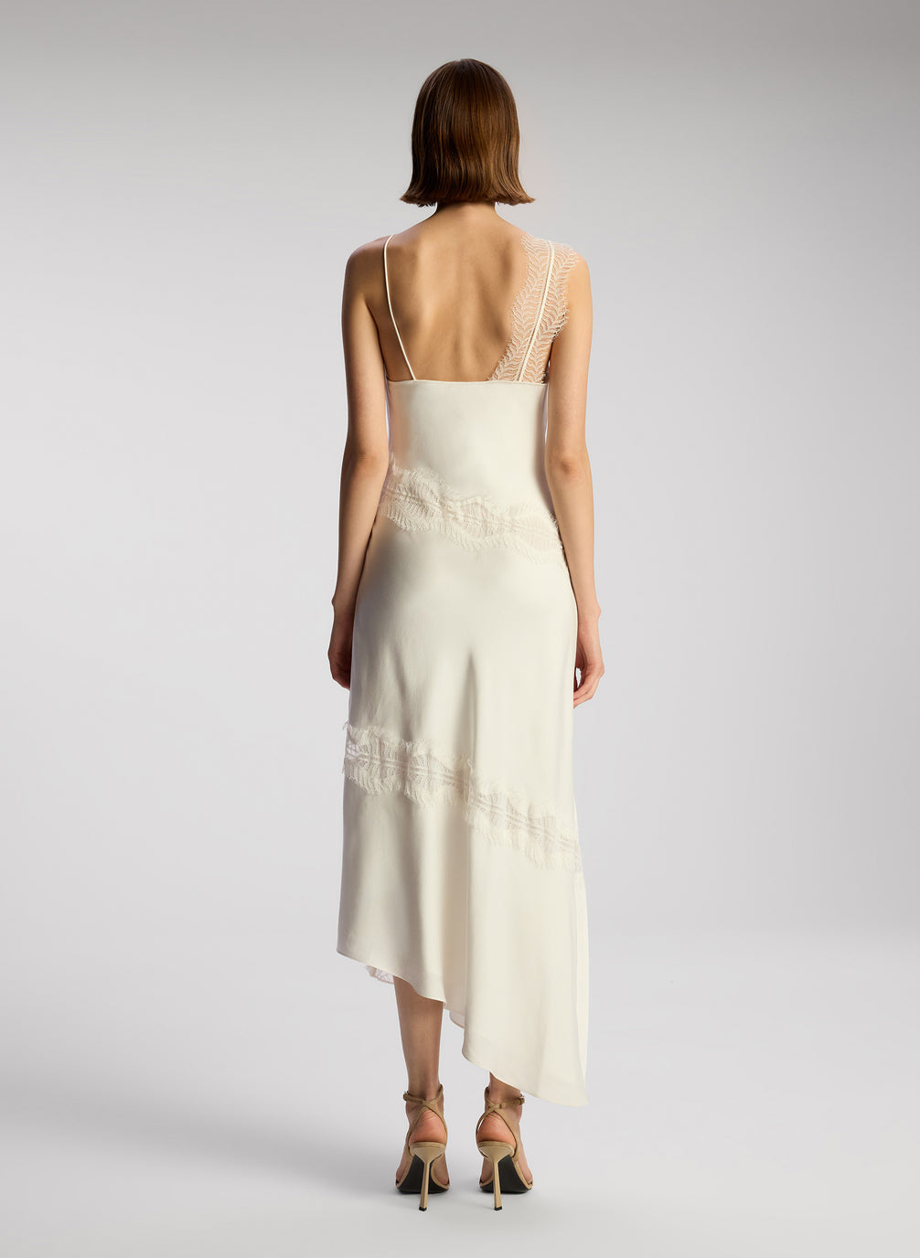 back view of woman wearing off white lace trimmed midi dress