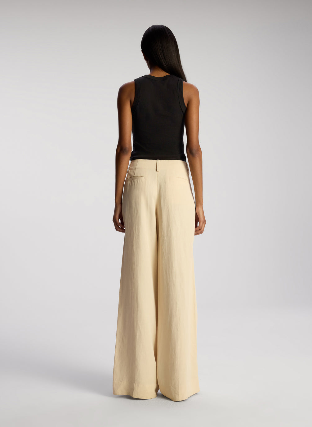 back view of woman wearing black tank top and beige pants