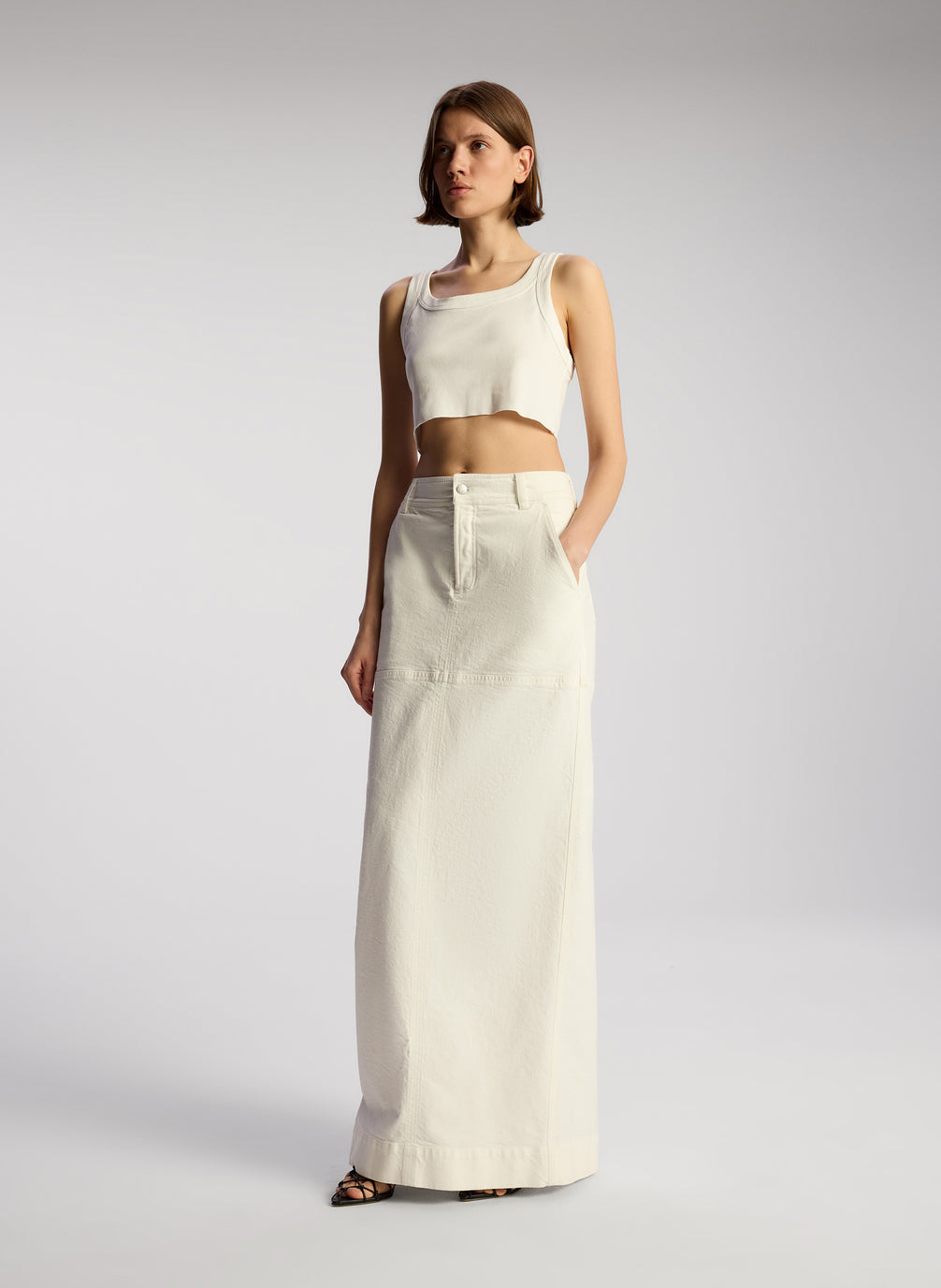 side view of woman wearing white cropped rib tank and white maxi skirt
