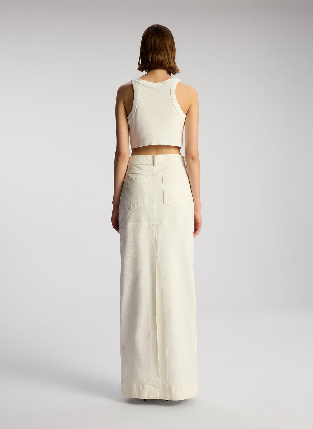 back view of woman wearing white cropped rib tank and white maxi skirt
