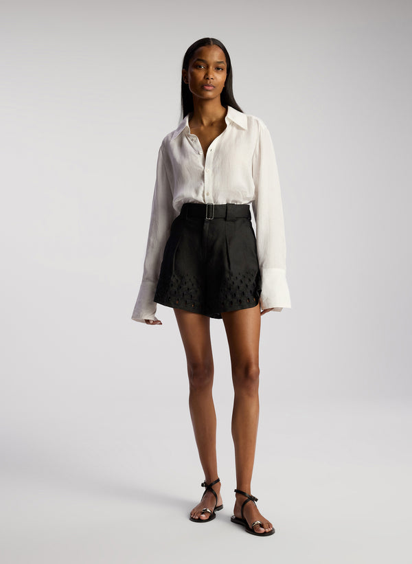 front view of woman wearing white linen button down shirt and black shorts