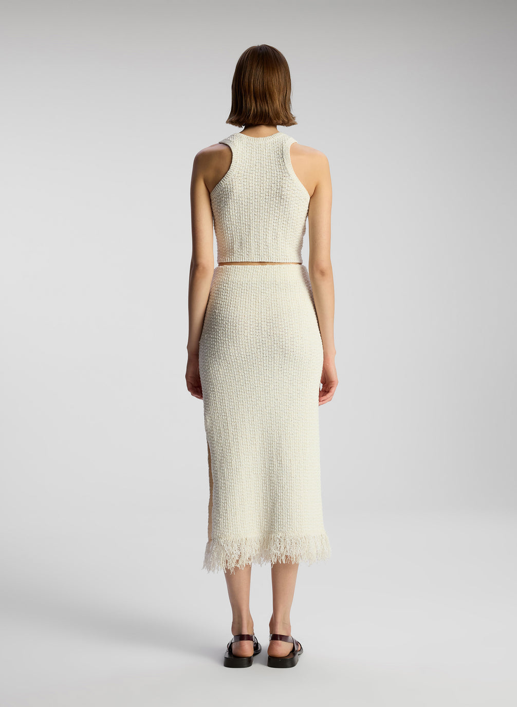 back view of woman wearing white knit sleeveless top and matching skirt