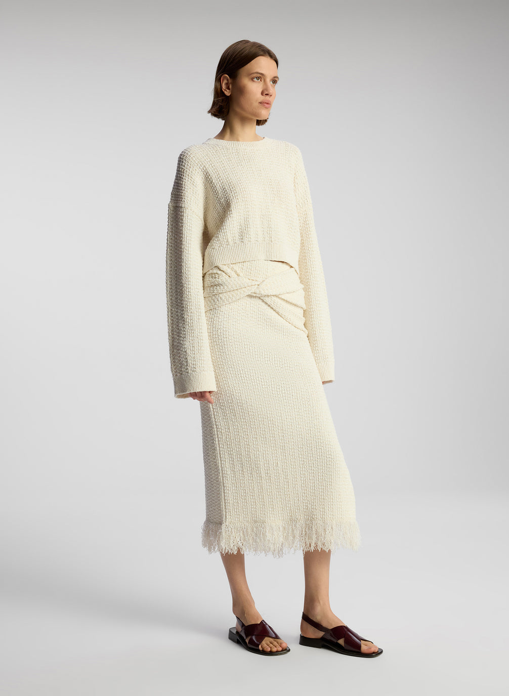 side view of woman wearing white pullover sweater and matching midi skirt