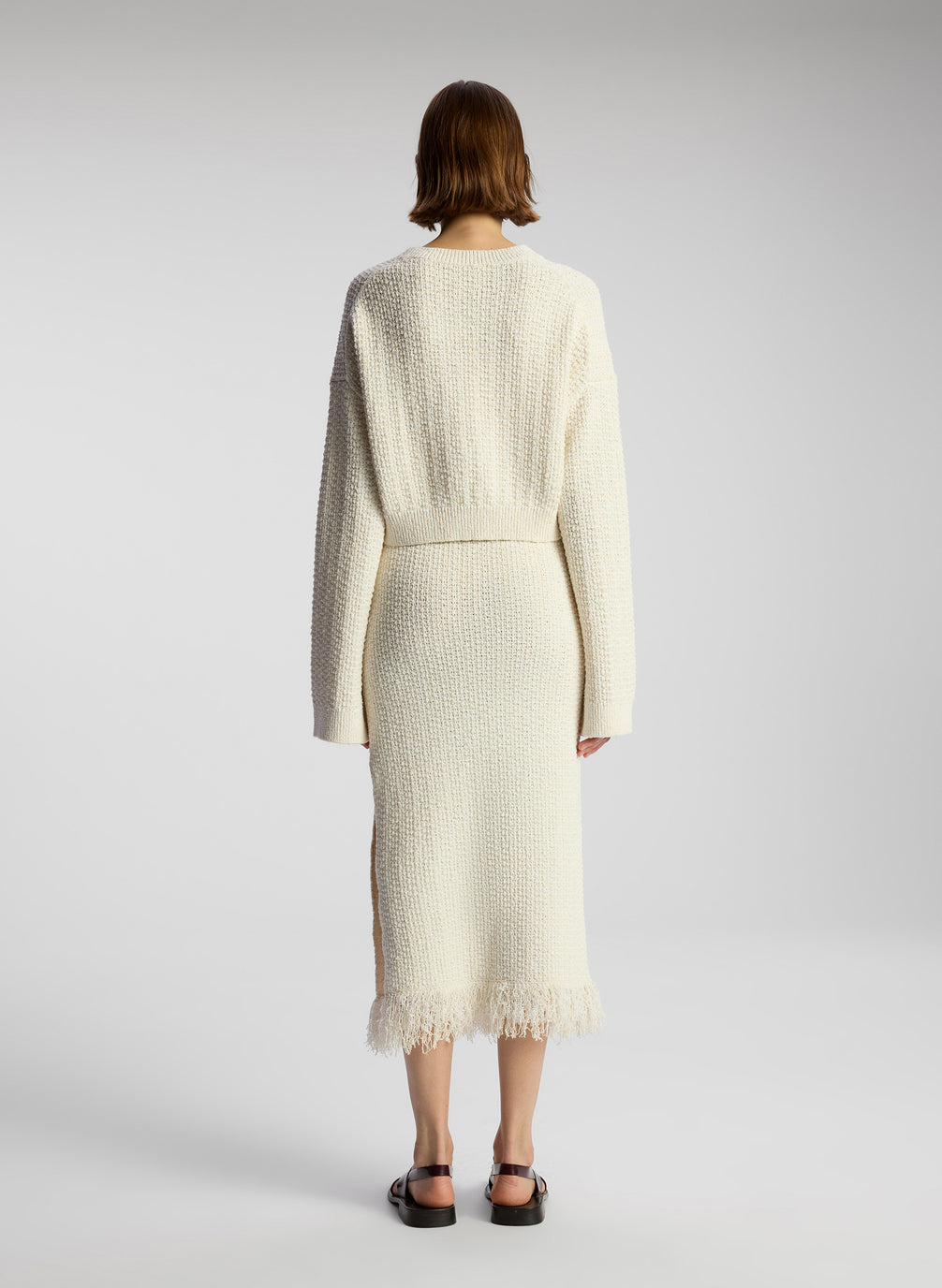 back view of woman wearing white pullover sweater and matching midi skirt