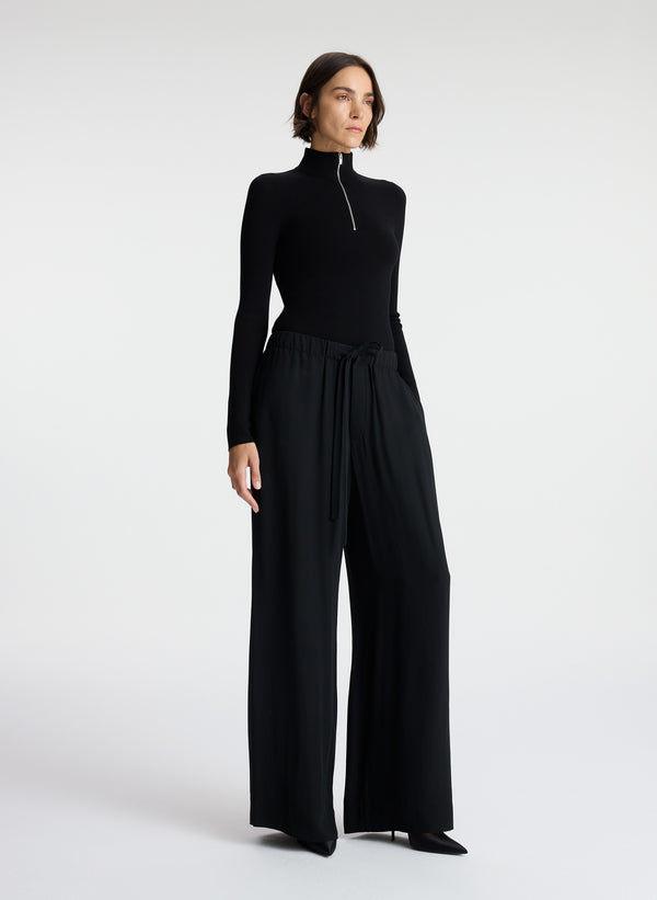 side view of woman wearing black knit top and black wide leg pants