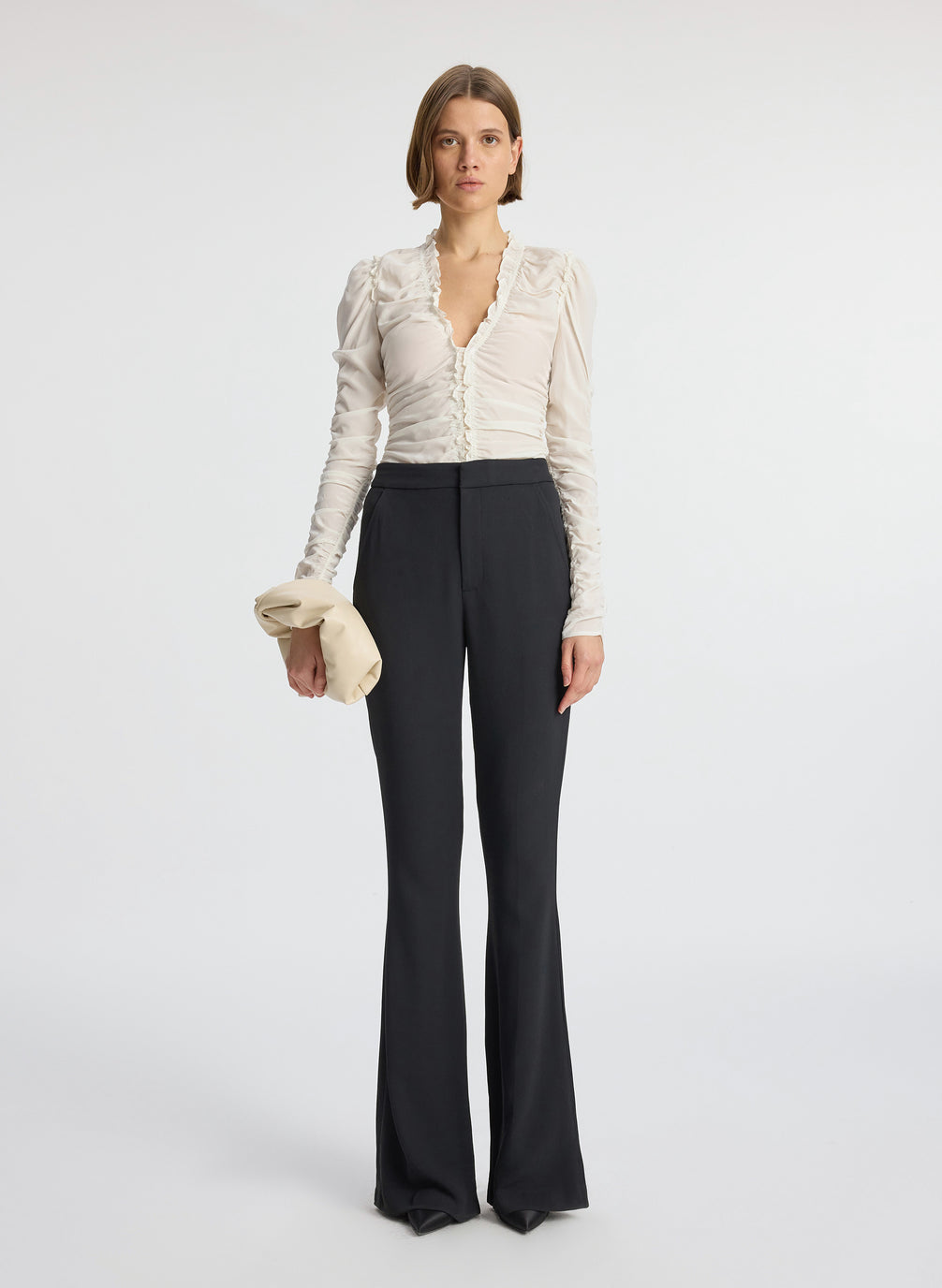 front view of woman wearing white long sleeve v neck top and black flared pants