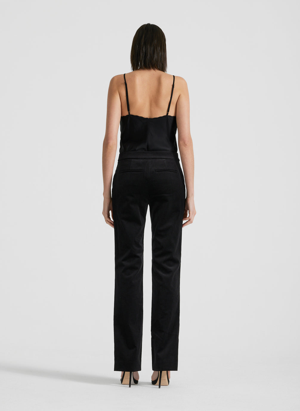 back view of woman wearing black satin camisole and black velvet pants