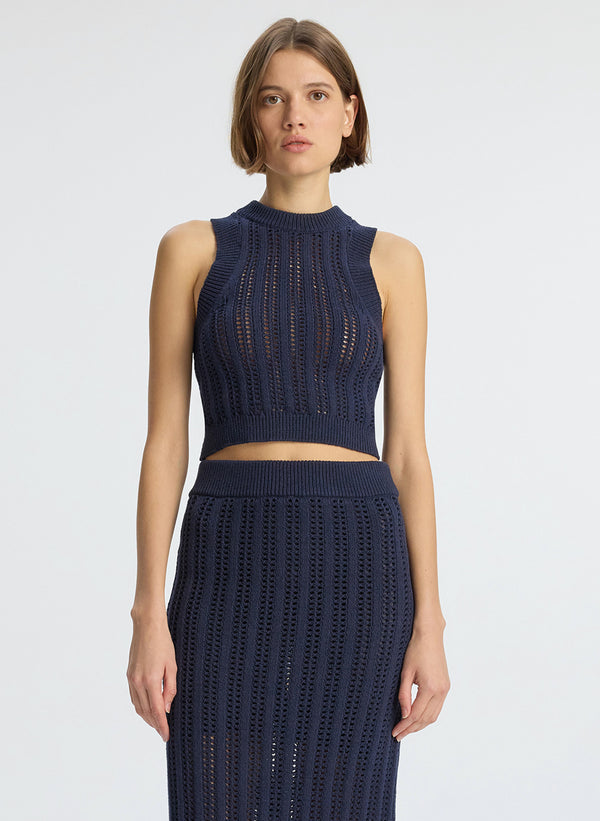 detail view of woman wearing navy blue open weave tank top and matching skirt