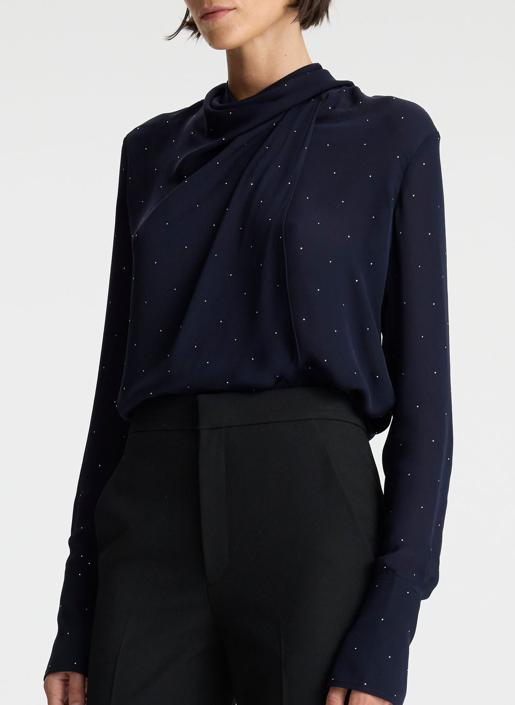 front view of woman wearing navy blue silk long sleeve top with crystal embellishments and black pants 