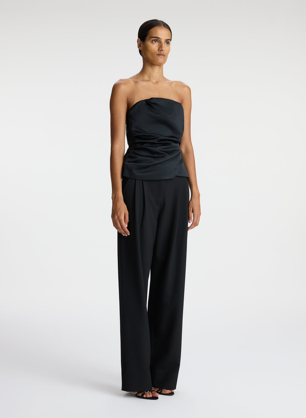 side  view of woman wearing black strapless satin top and black pants
