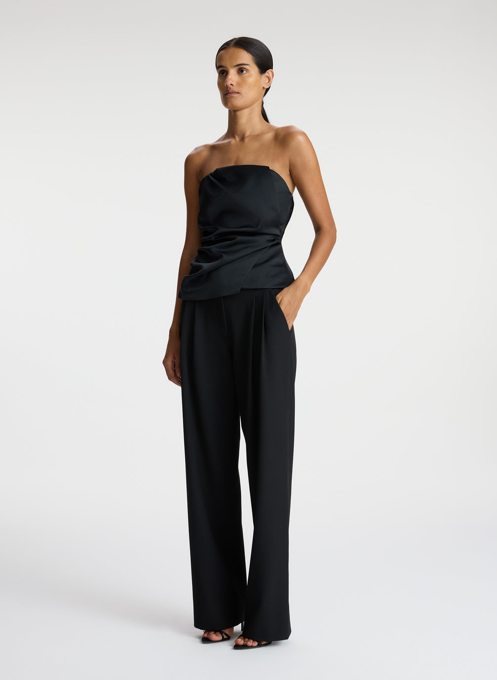 side  view of woman wearing black strapless satin top and black pants