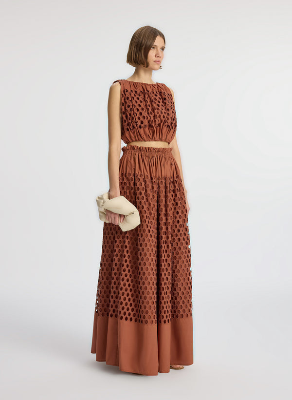 side view of woman wearing brown sleeveless top and matching maxi skirt