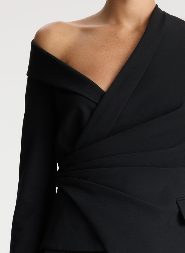 detail view of woman wearing black long sleeve asymmetric top and black pants