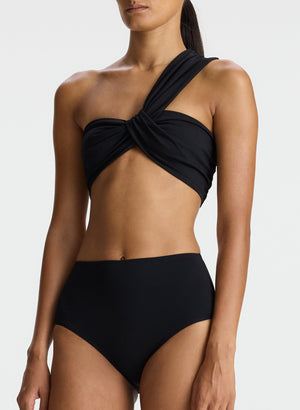 detail view of woman wearing black one shoulder swimsuit top and bikini bottom