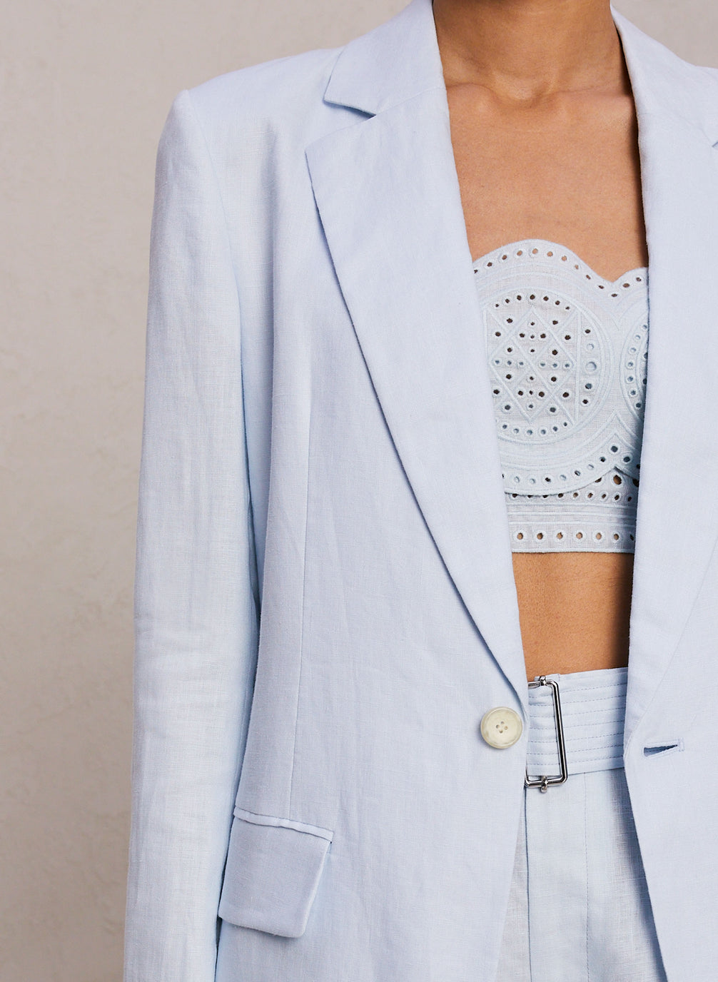 detail view of woman wearing light blue eyelet crop tank and coordinating short with blazer