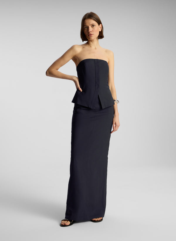 front view of woman wearing navy blue strapless top and matching maxi skirt