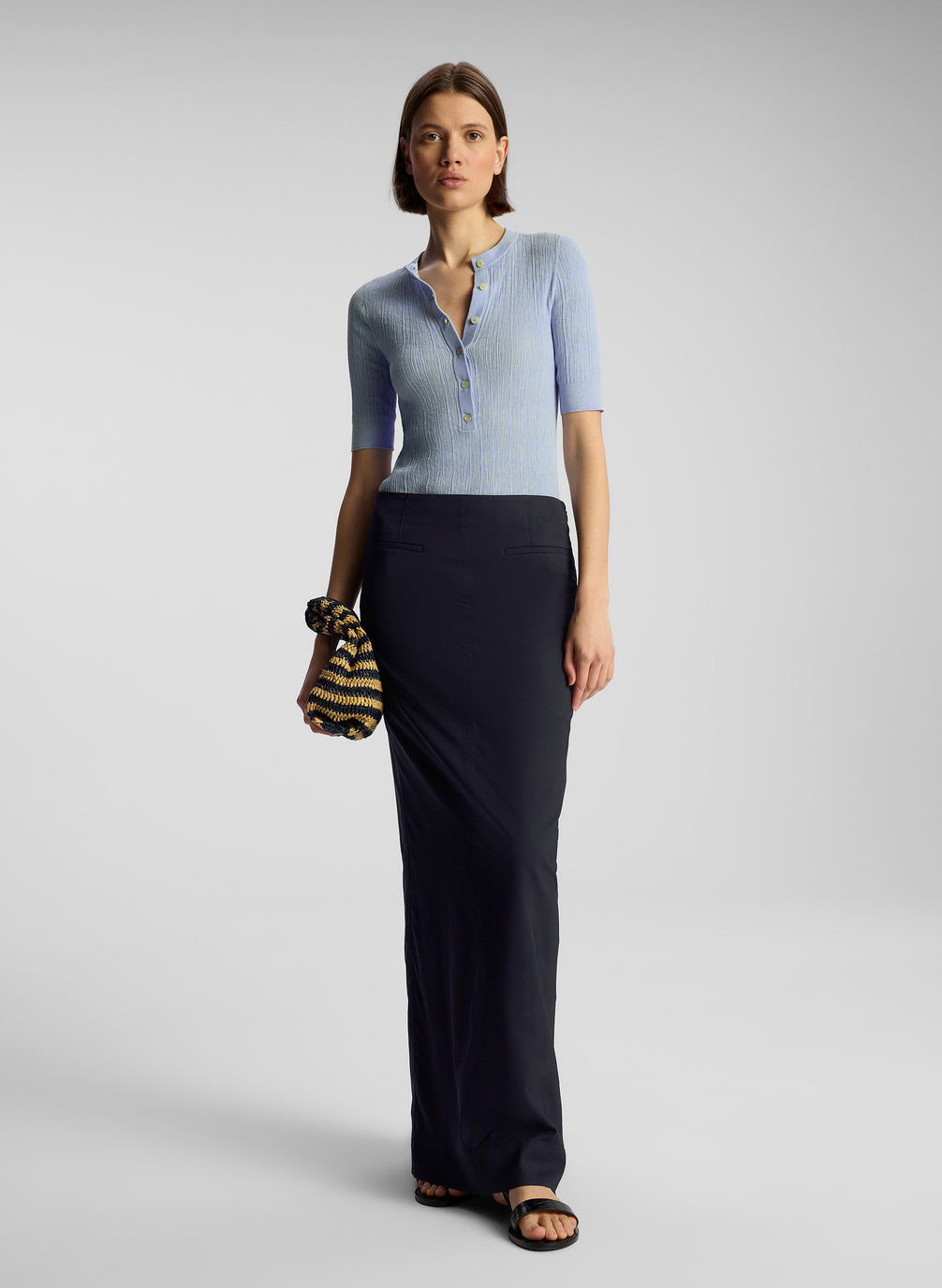 front view of woman wearing light blue shirt and navy blue maxi skirt