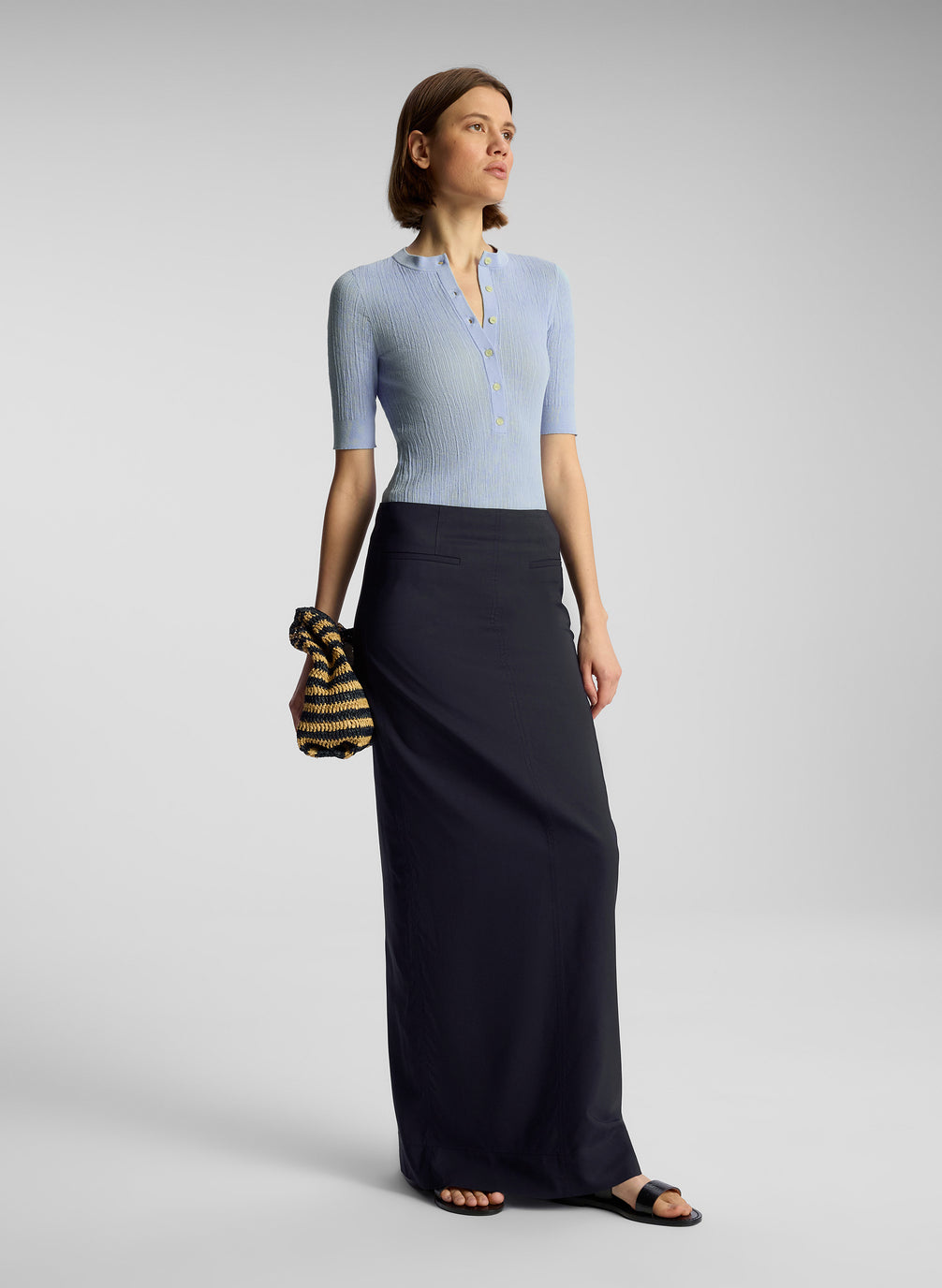 side  view of woman wearing light blue shirt and navy blue maxi skirt