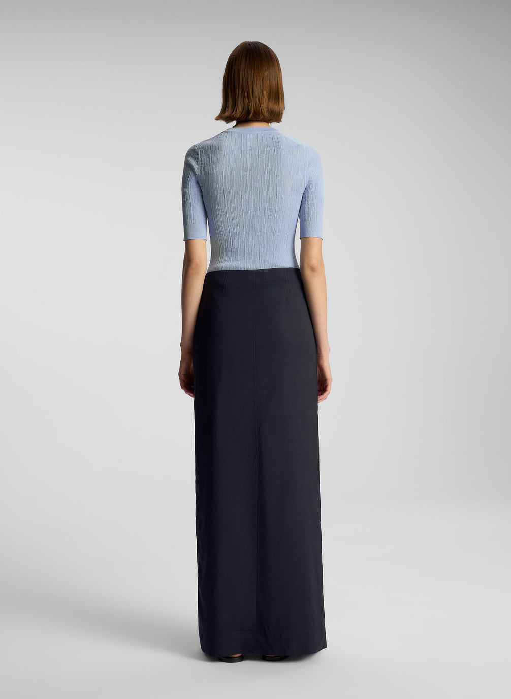 back  view of woman wearing light blue shirt and navy blue maxi skirt