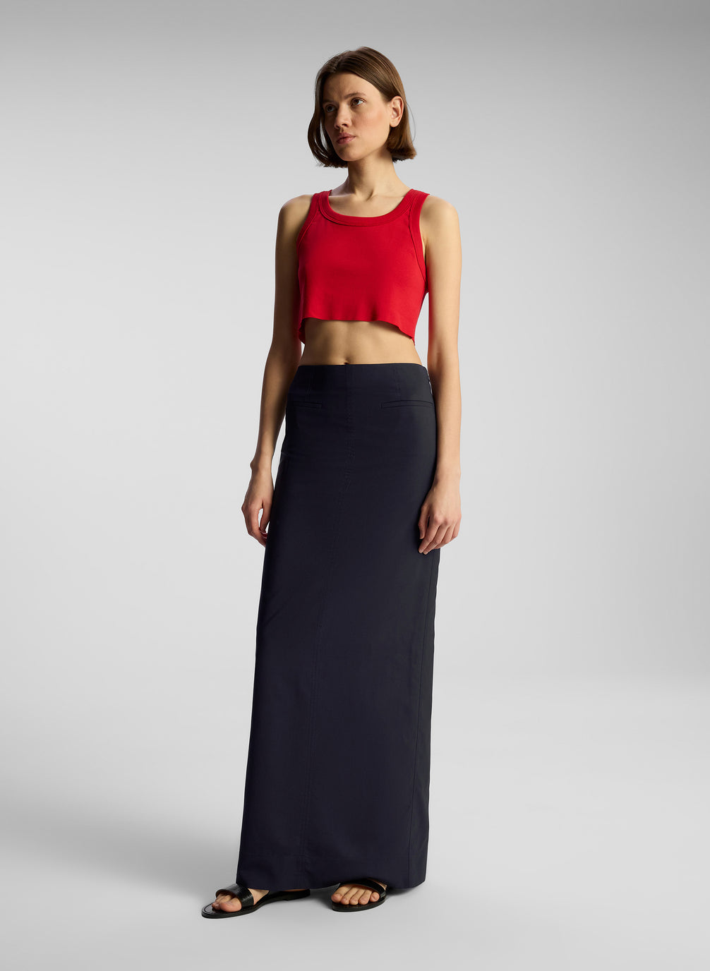 side view of woman wearing red cropped tank top and nay blue maxi skirt