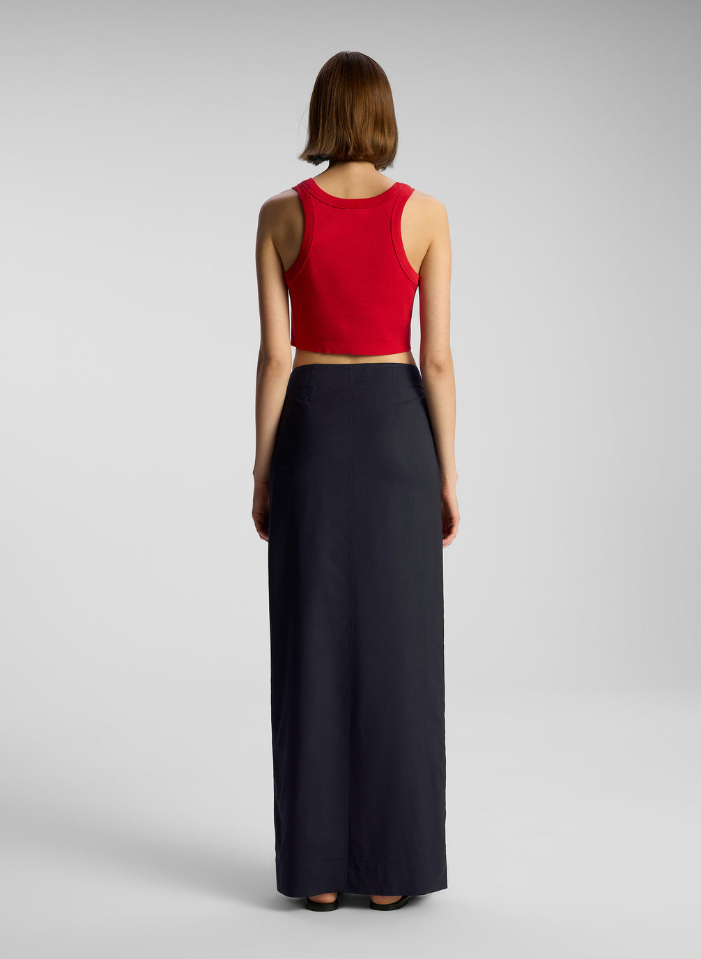 back view of woman wearing red cropped tank top and nay blue maxi skirt
