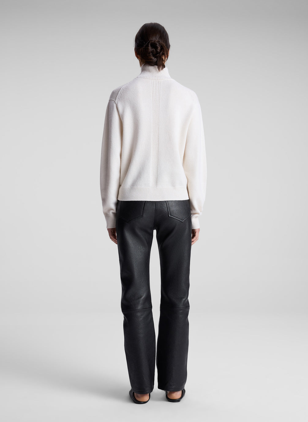 woman wearing cream sweater and black leather pants