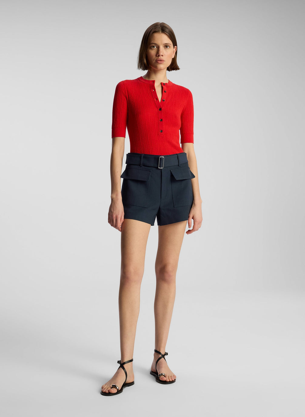 front view of woman wearing red top and navy blue shorts