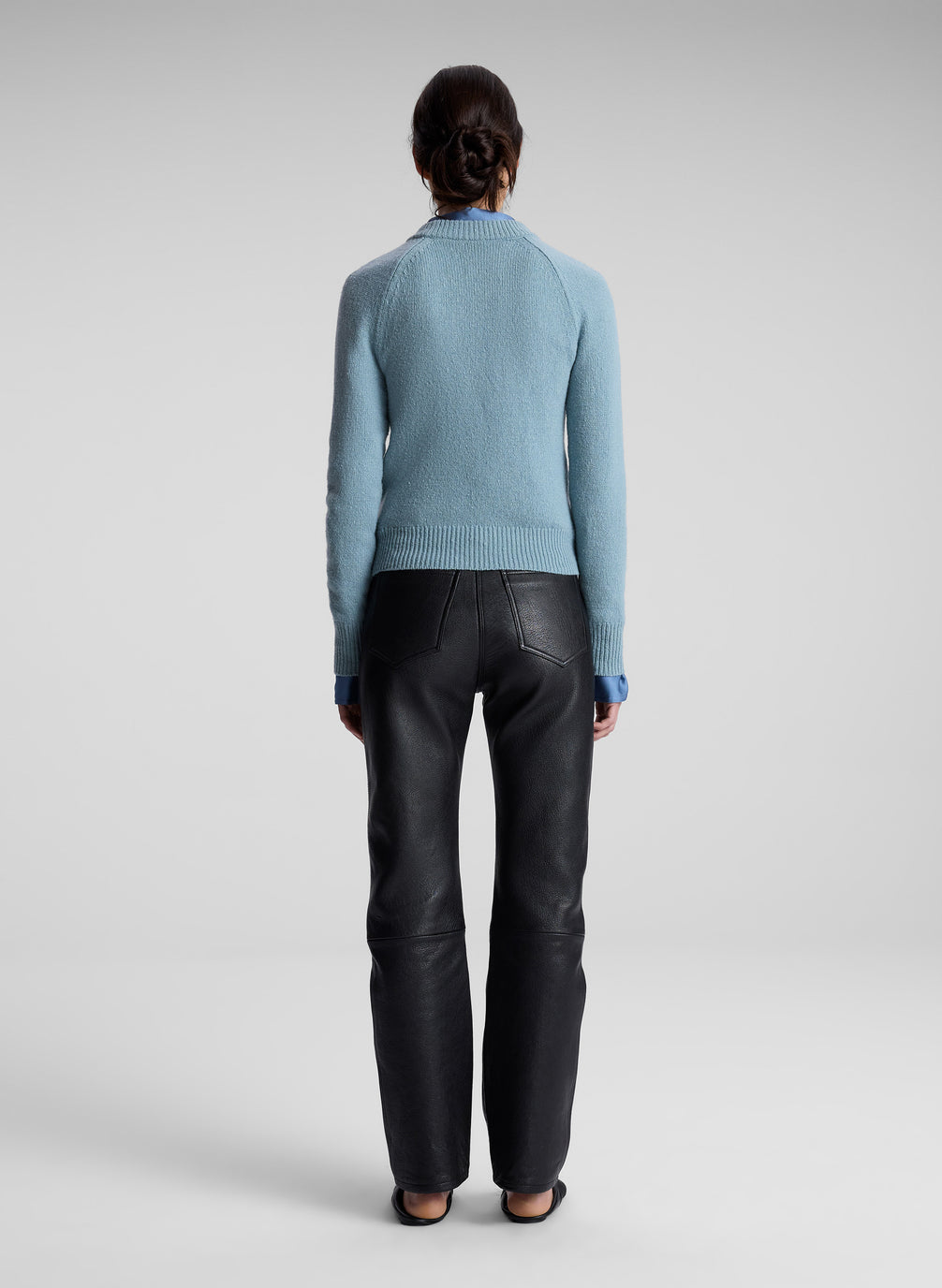 woman wearing blue sweater, blue shirt and black leather pants