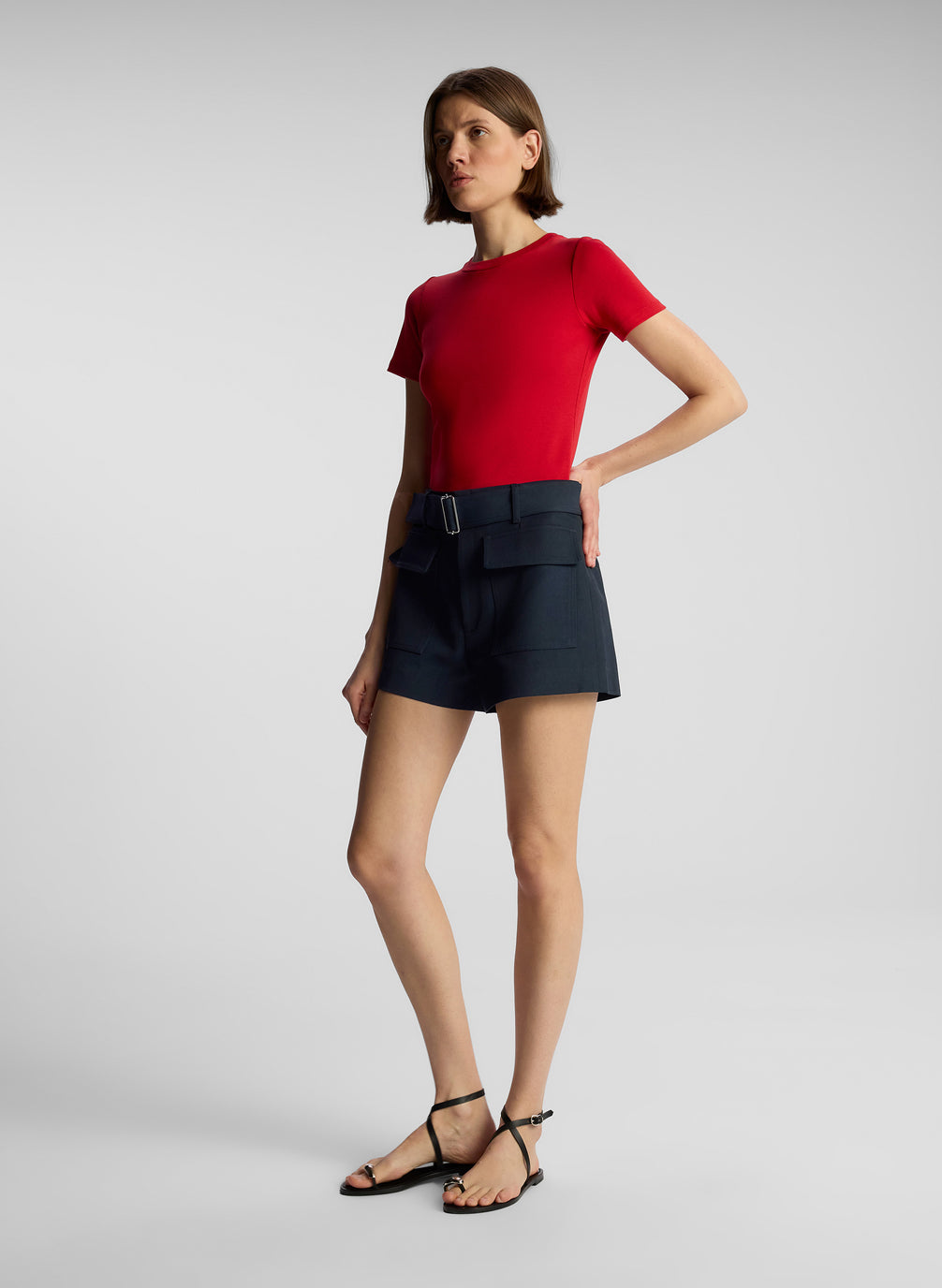 side  view of woman wearing red t shirt and navy blue shorts