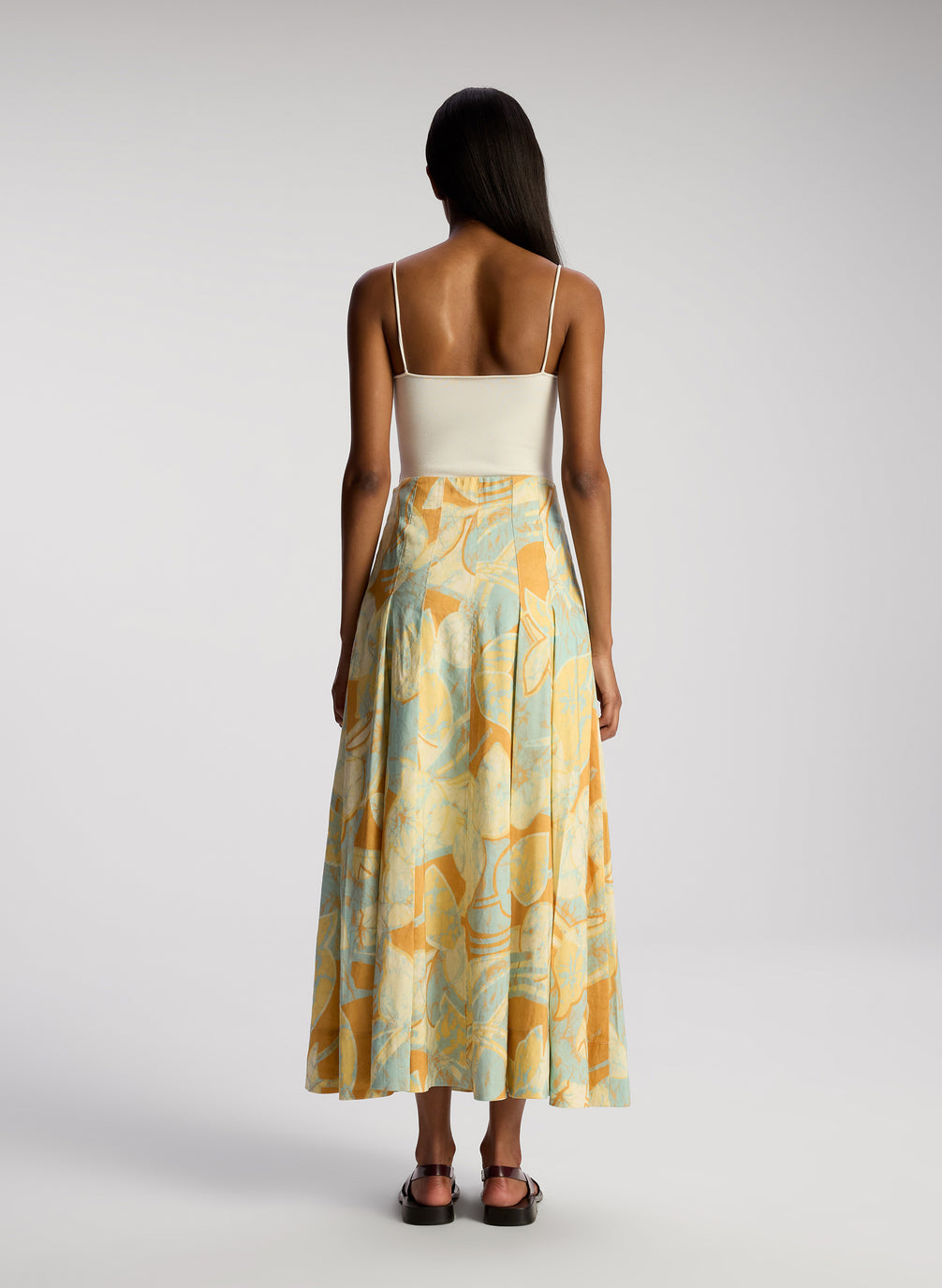 back view of woman wearing whit bodysuit and multicolor midi skirt
