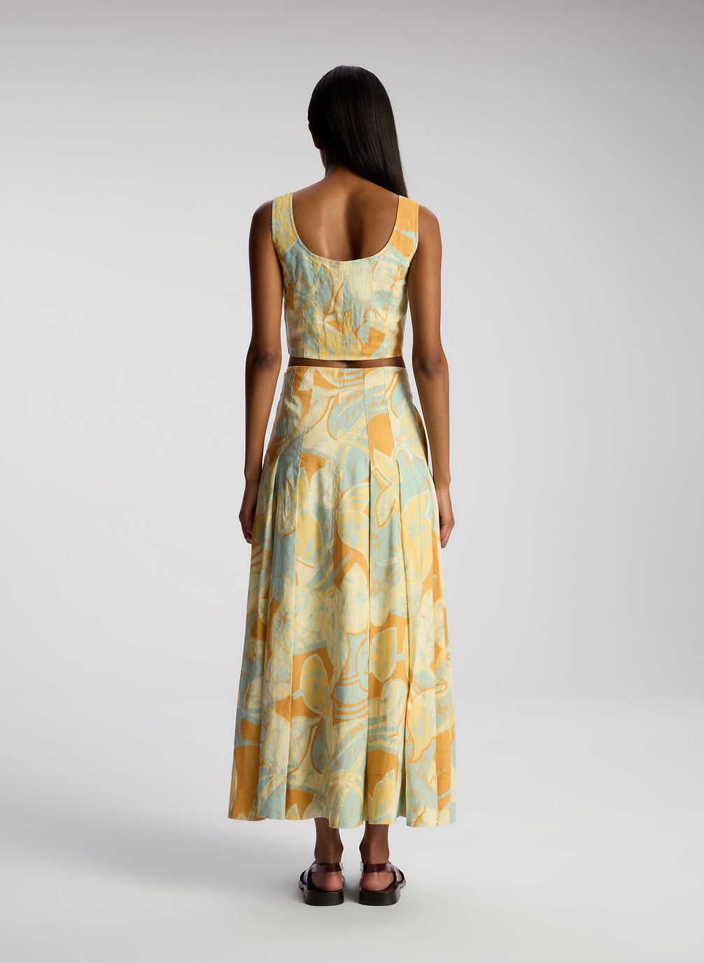 back view of woman wearing multicolor cropped sleeveless tops and matching midi skirt