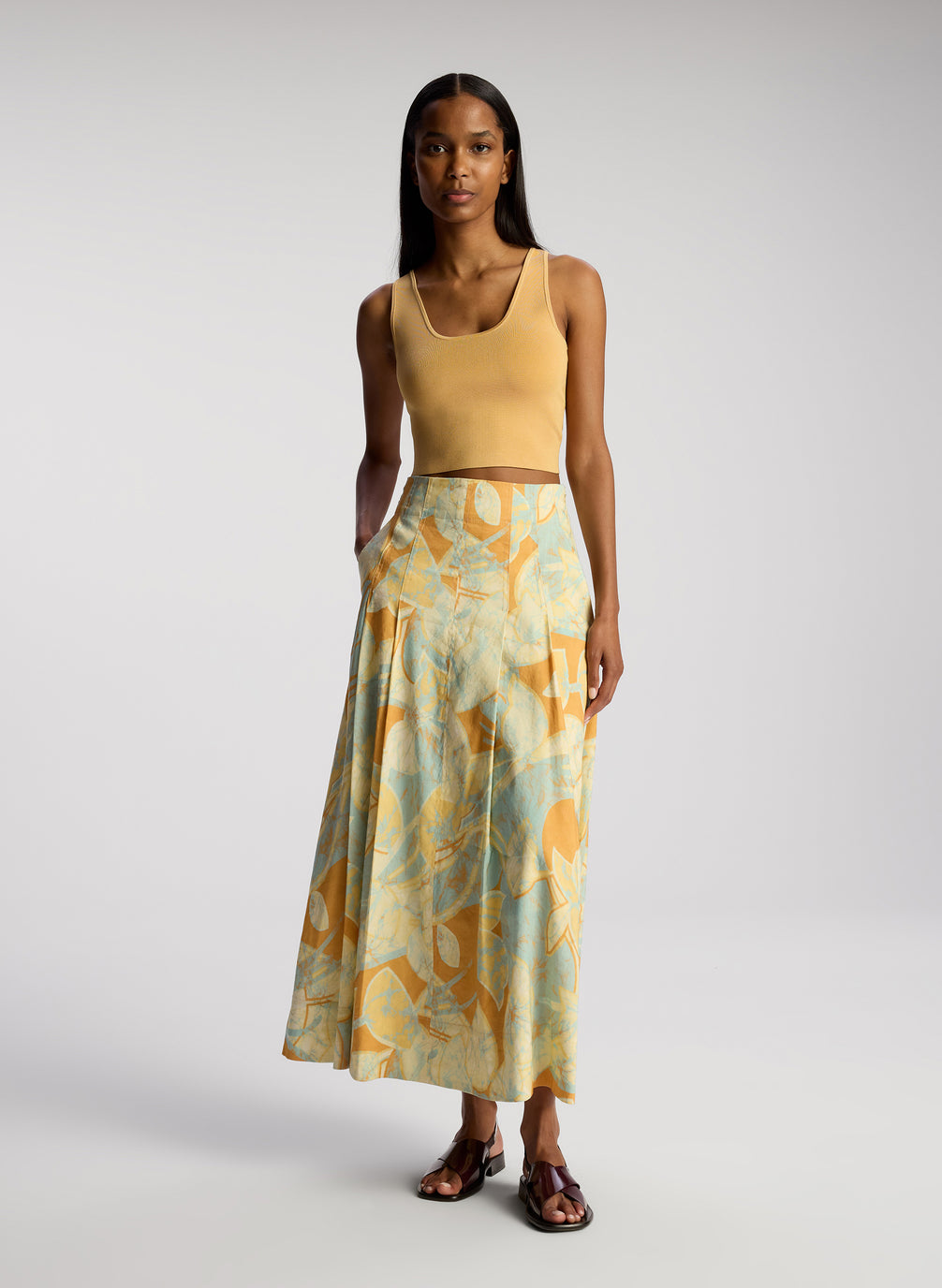 front view of woman wearing tan sleeveless top with multicolor printed midi skirt