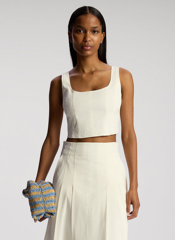 front view of woman wearing white sleeveless cropped top and white midi skirt