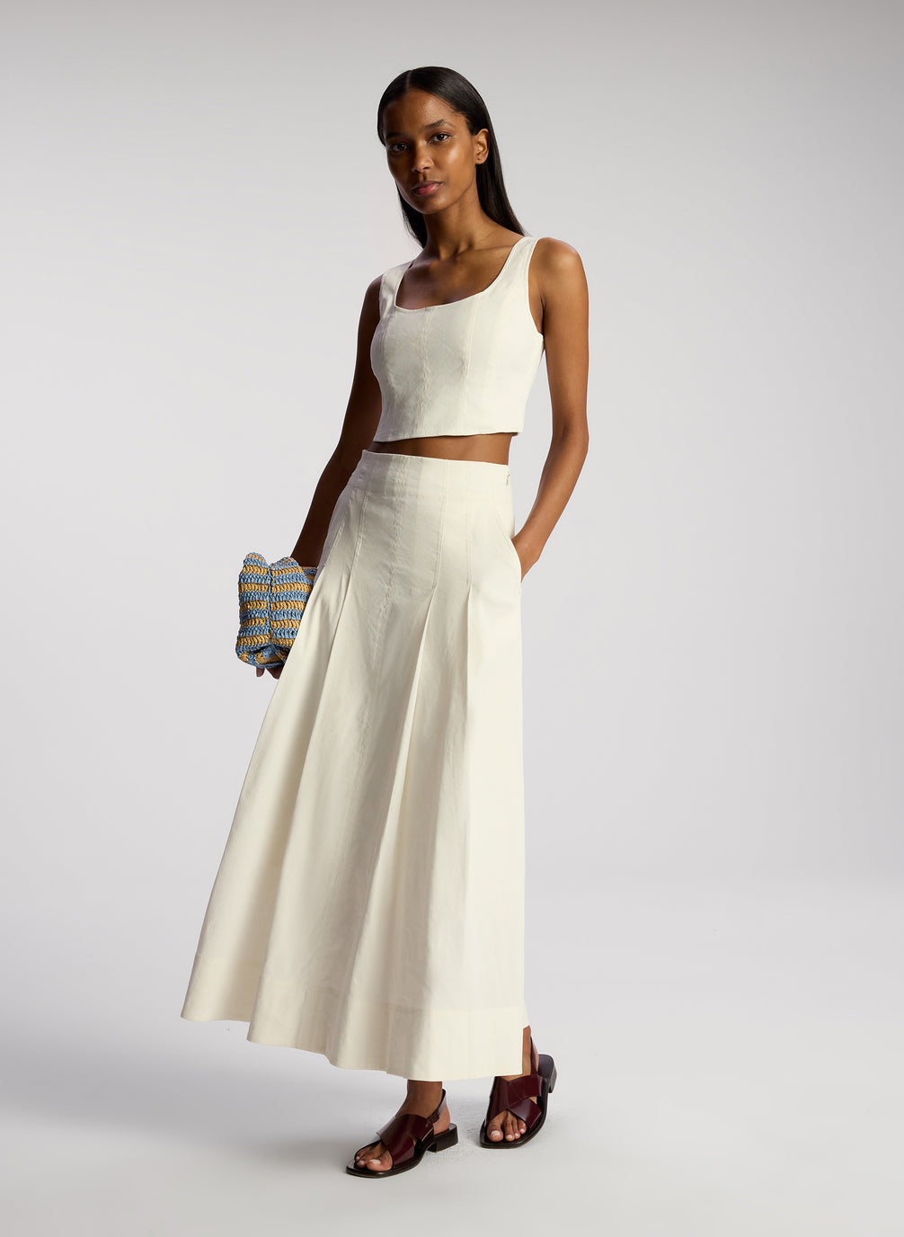 side view of woman wearing white sleeveless cropped top and white midi skirt