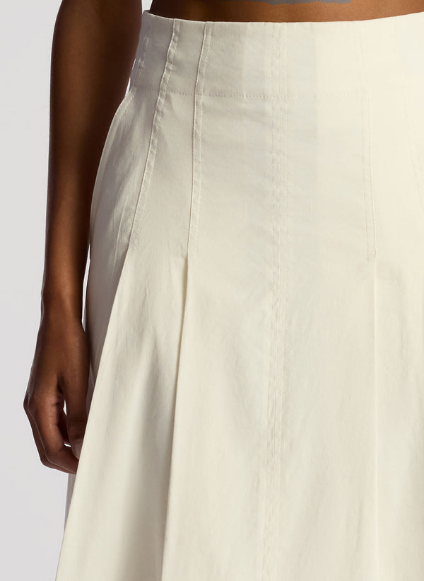 detail view of woman wearing white sleeveless cropped top and white midi skirt