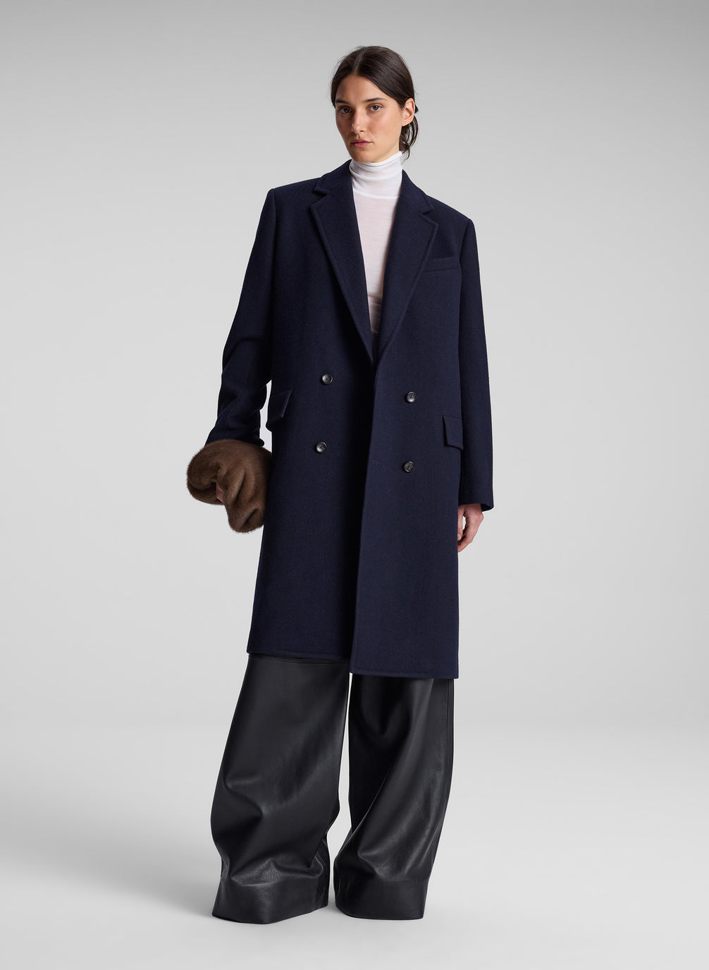 woman wearing navy blue coat and black pants and white turtleneck