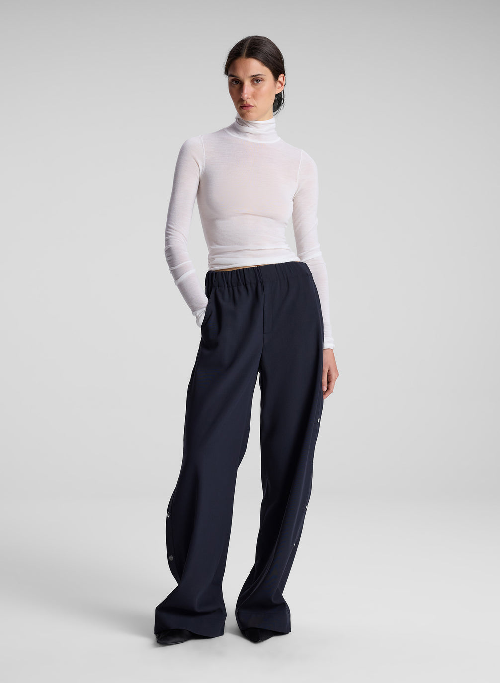 woman wearing white turtleneck and navy track pants