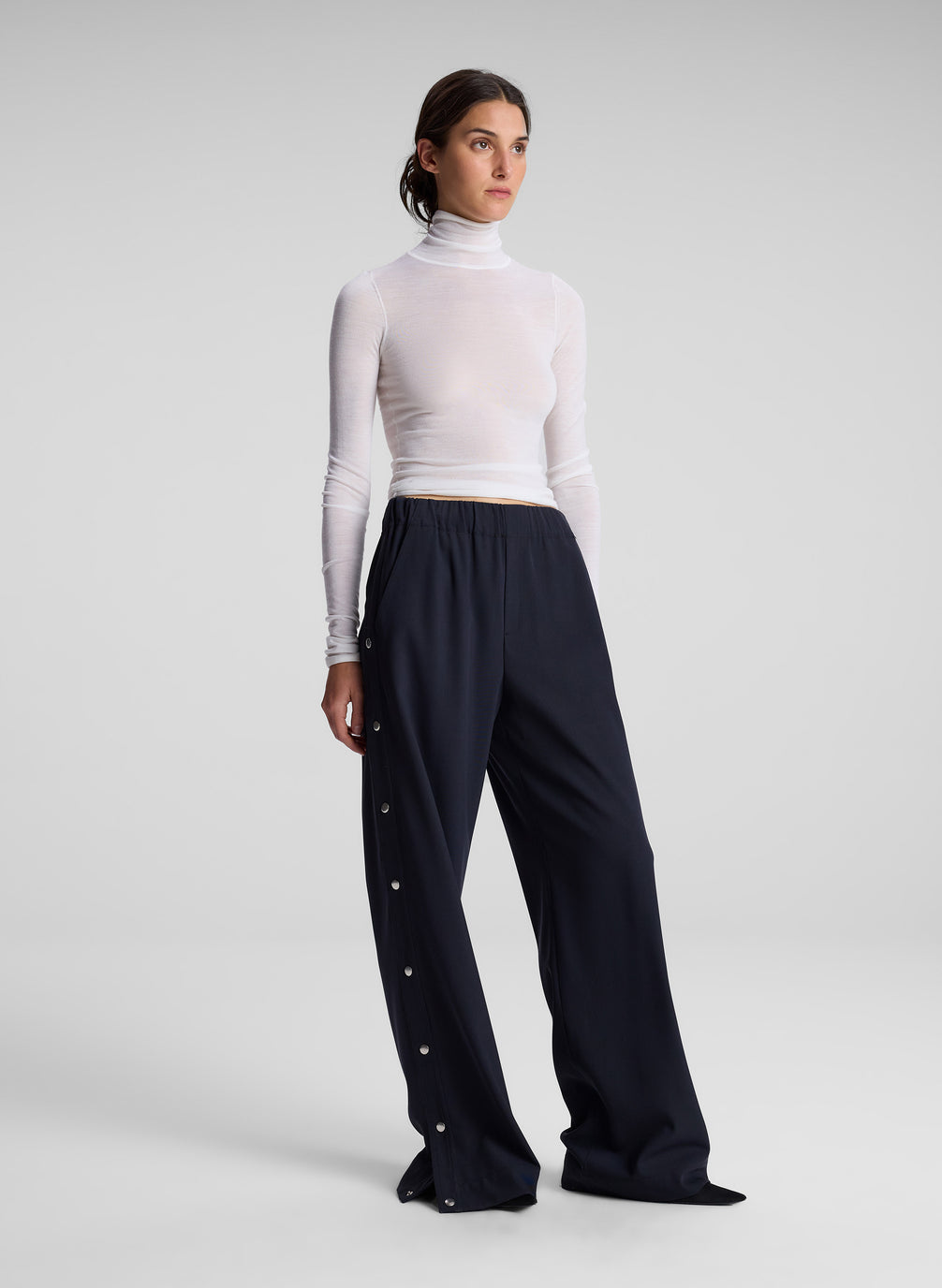 woman wearing white turtleneck and navy track pants