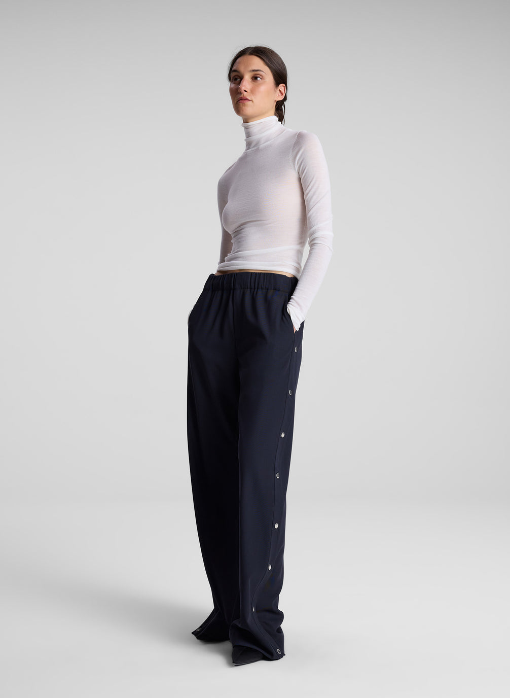 woman wearing white turtleneck and navy track pants