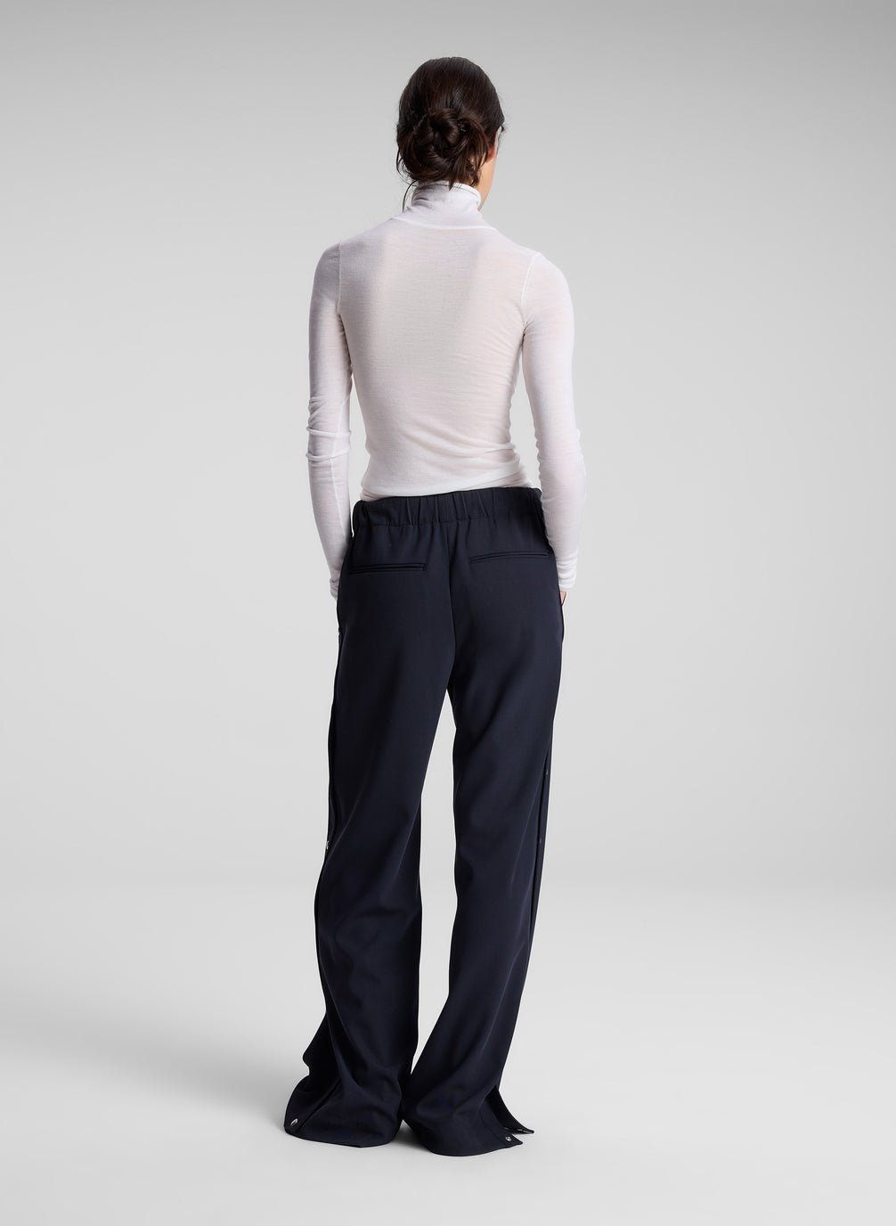 woman wearing white turtleneck and navy track pants