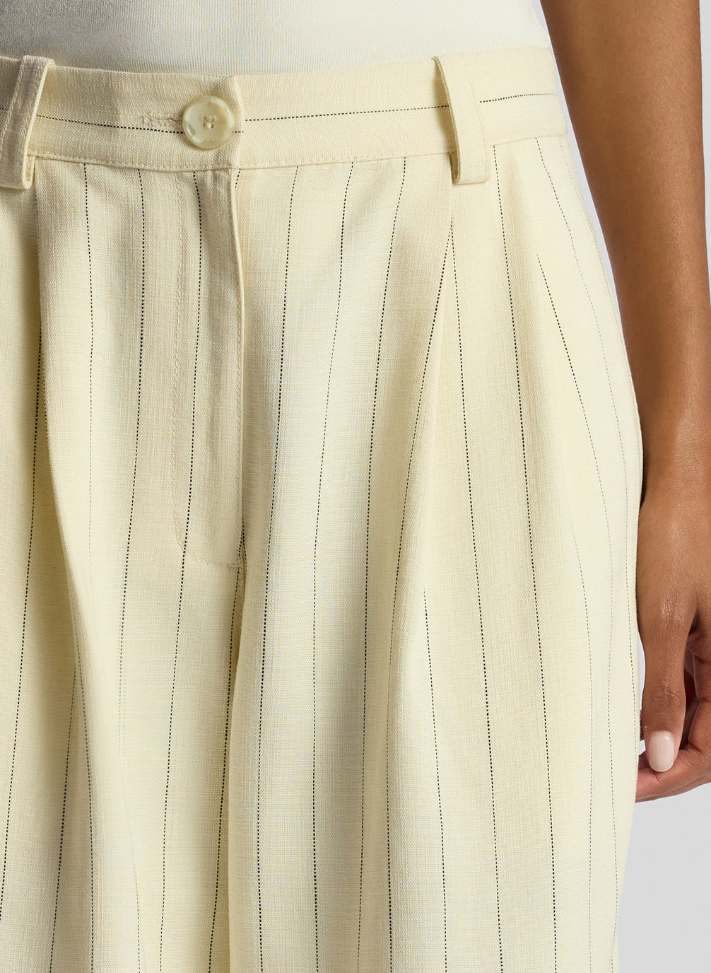 detail view of woman earing cream bodysuit and cream pinstripe pant