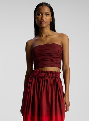front view of woman wearing burgundy strapless top and matching midi skirt