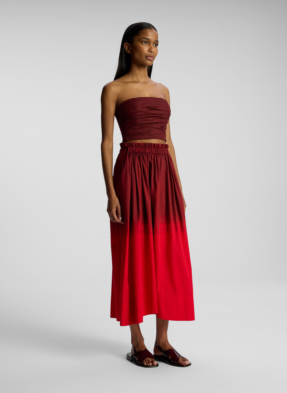 side view of woman wearing burgundy and red ombre top and skirt