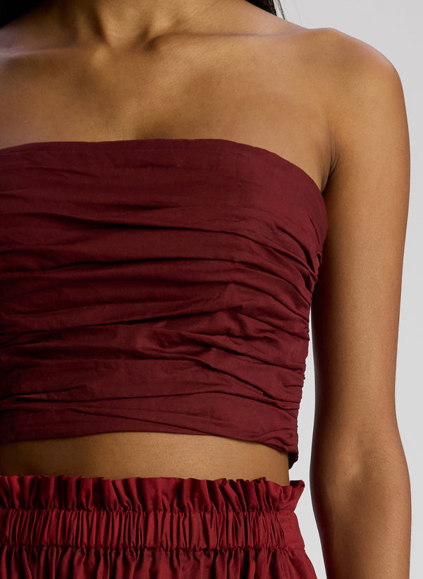detail view of woman wearing burgundy strapless top and matching midi skirt
