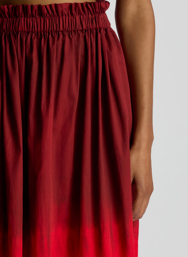 detail view of woman wearing burgundy and red ombre top and skirt