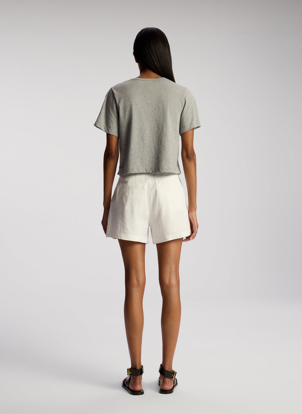back view of woman wearing grey tshirt and white shorts